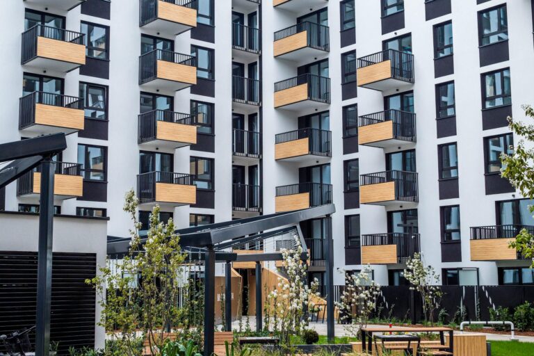 Contemporary apartment building with balconies and garden in spring.